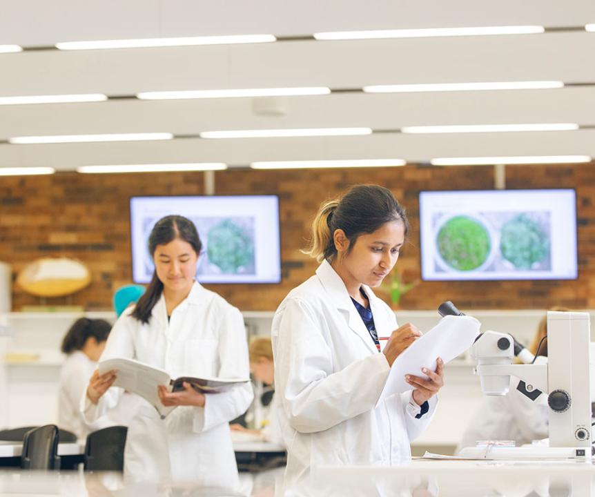Two female students working a science lab.
