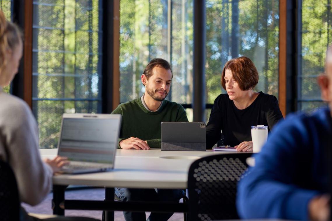 Staff talk over laptops in a room looking out over greenery